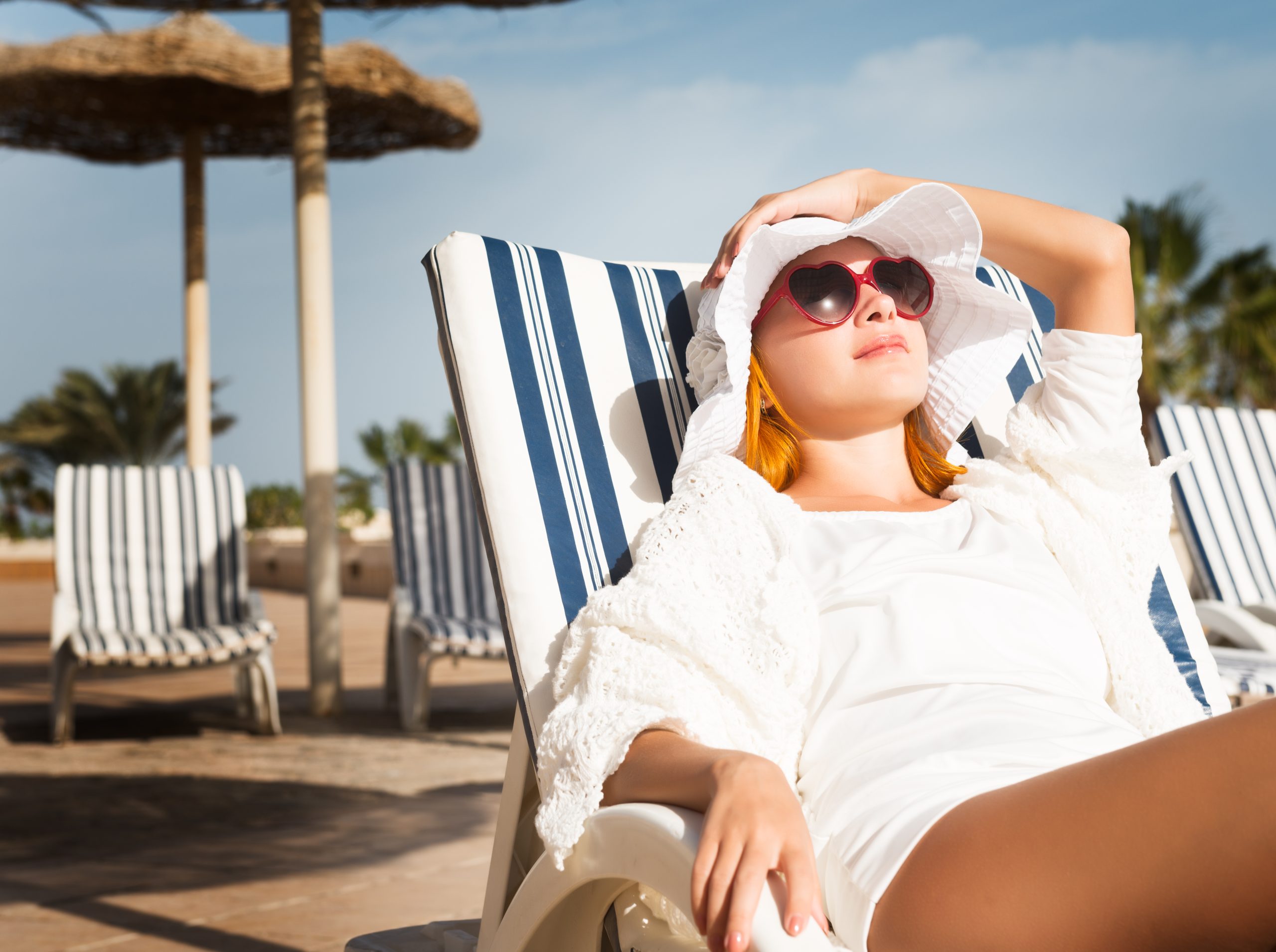 Young woman enjoying sun on sunbed at tourist resort