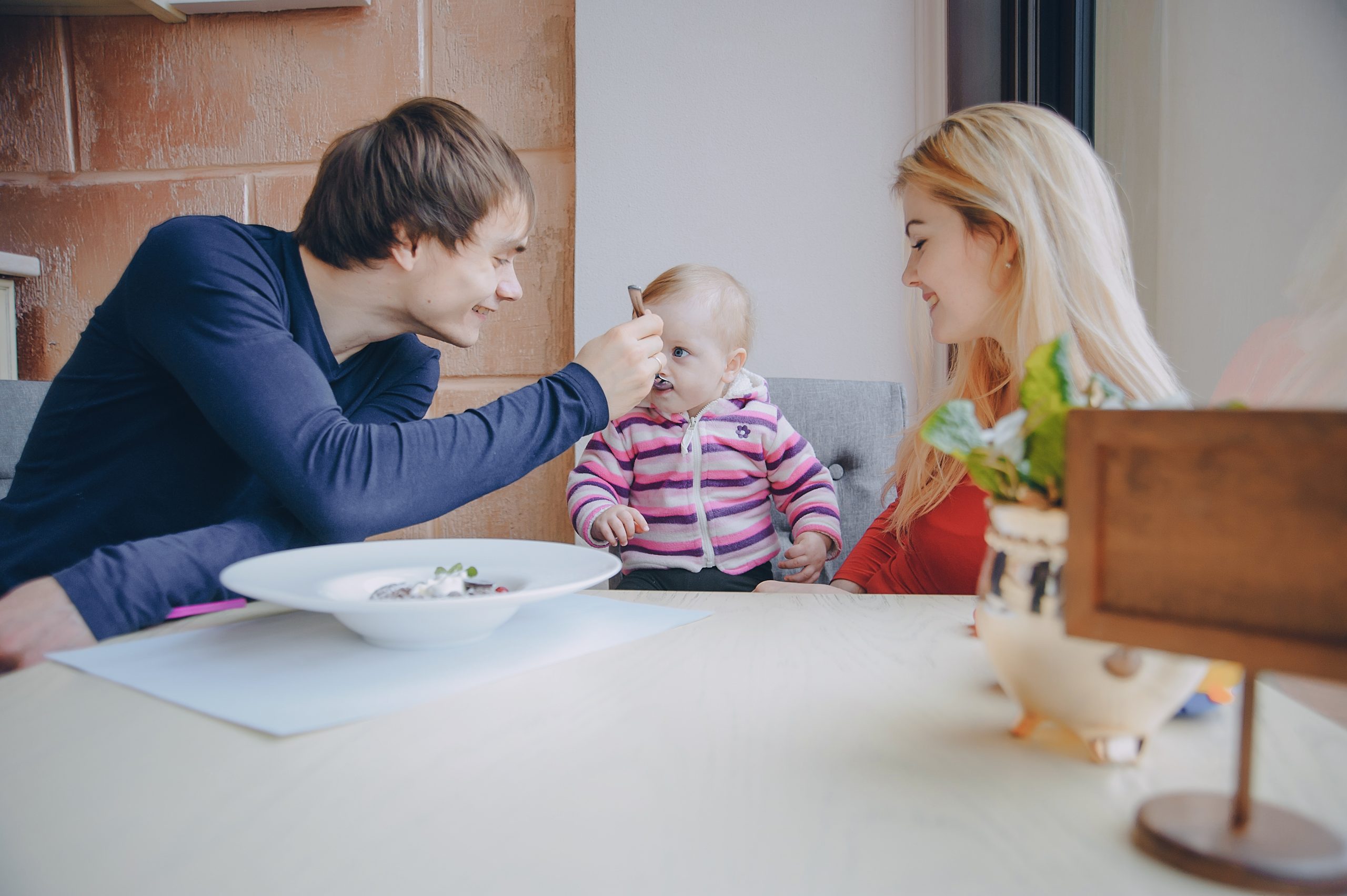 Mom Dad and their little daughter sitting in a cafe near the window